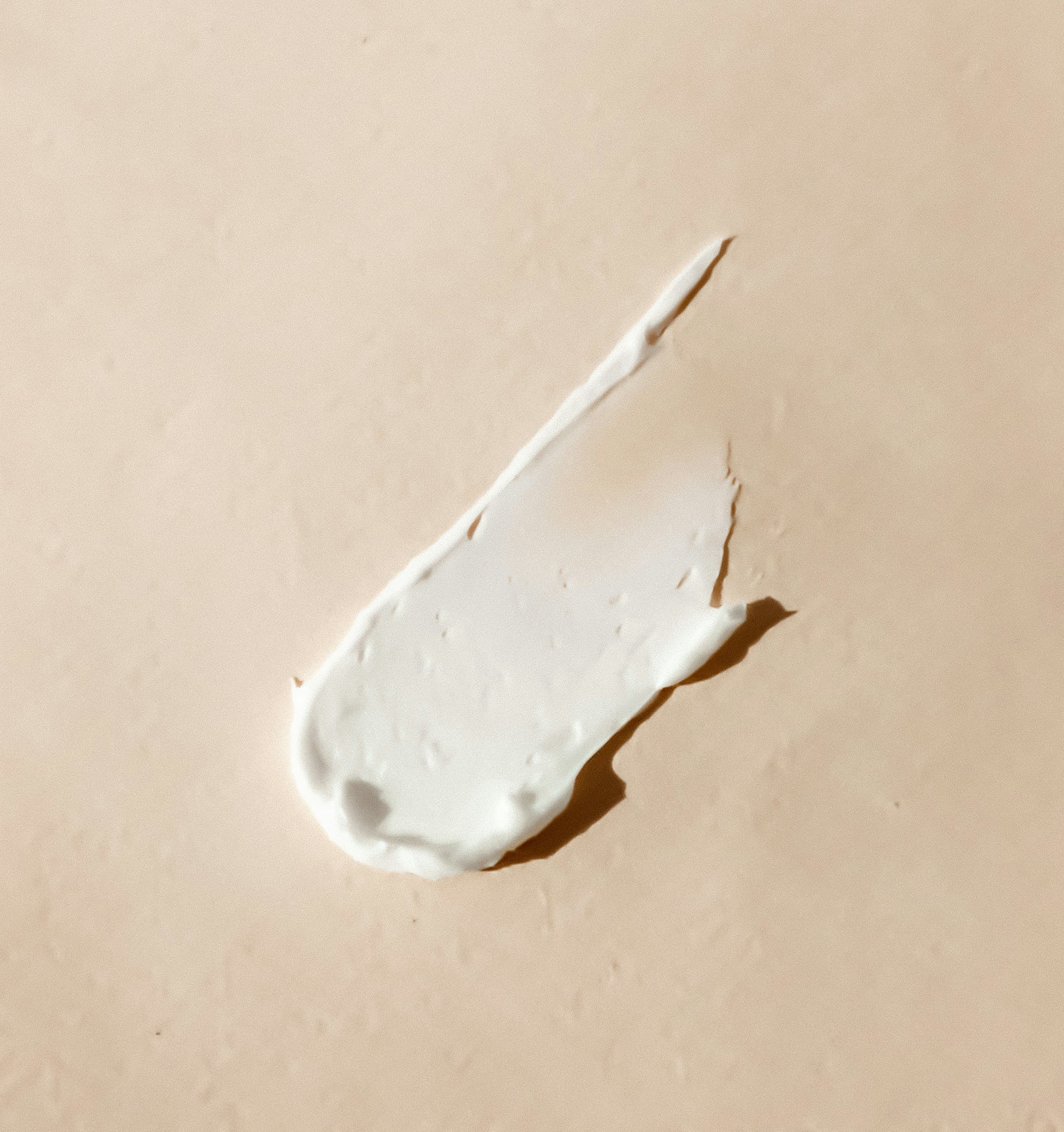 White cream swatch smeared across a beige surface