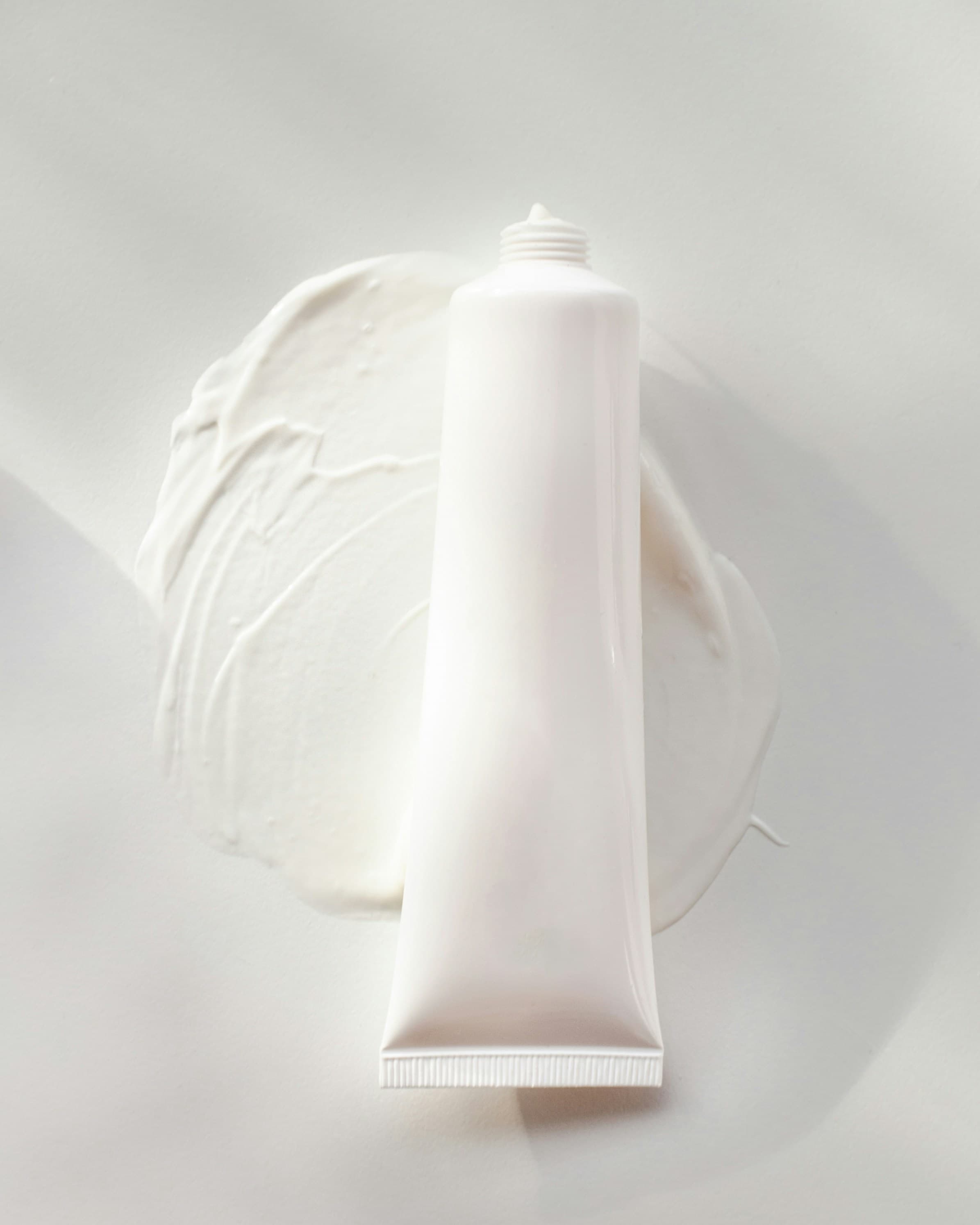 Cosmetic cream dispensed from a tube onto a white dish