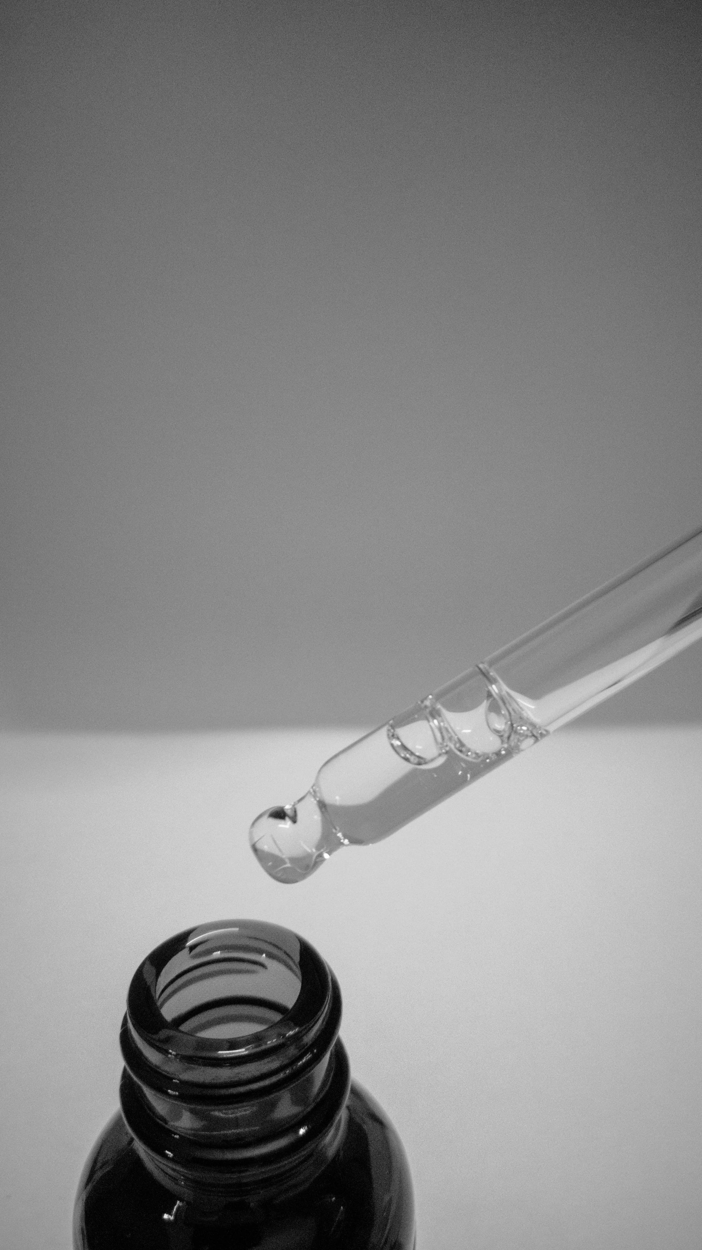 Glass bottle holding a clear cosmetic liquid