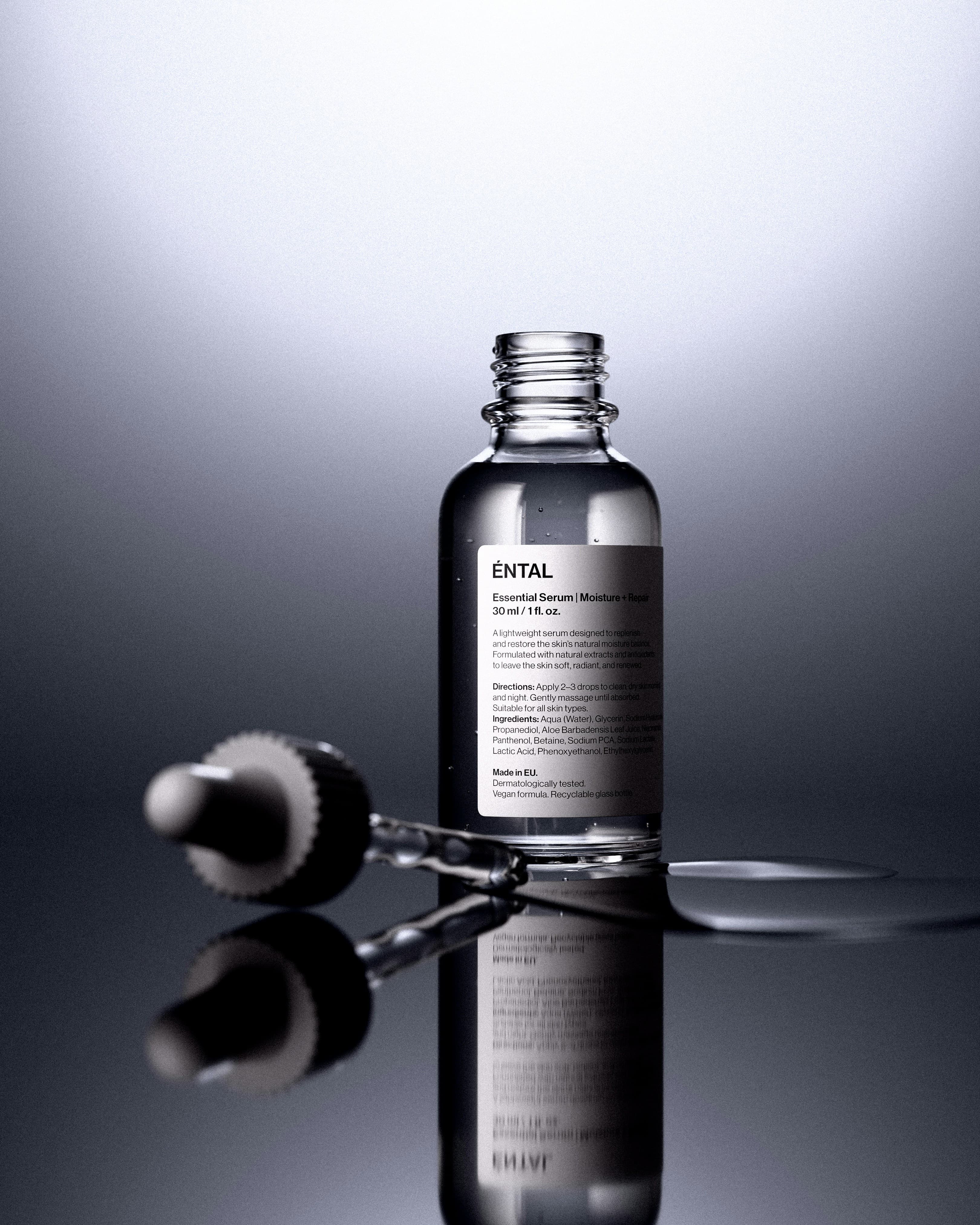 Clear serum bottle with dropper on a reflective surface